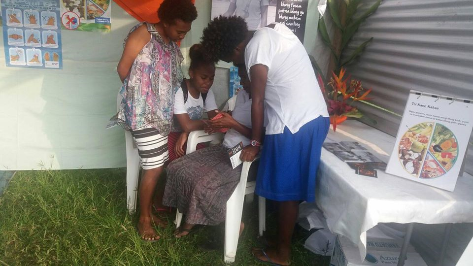 A World Vision Staff member is demonstrating the consent video game Rispek Danis to three youth ni-Vanuatu girls.